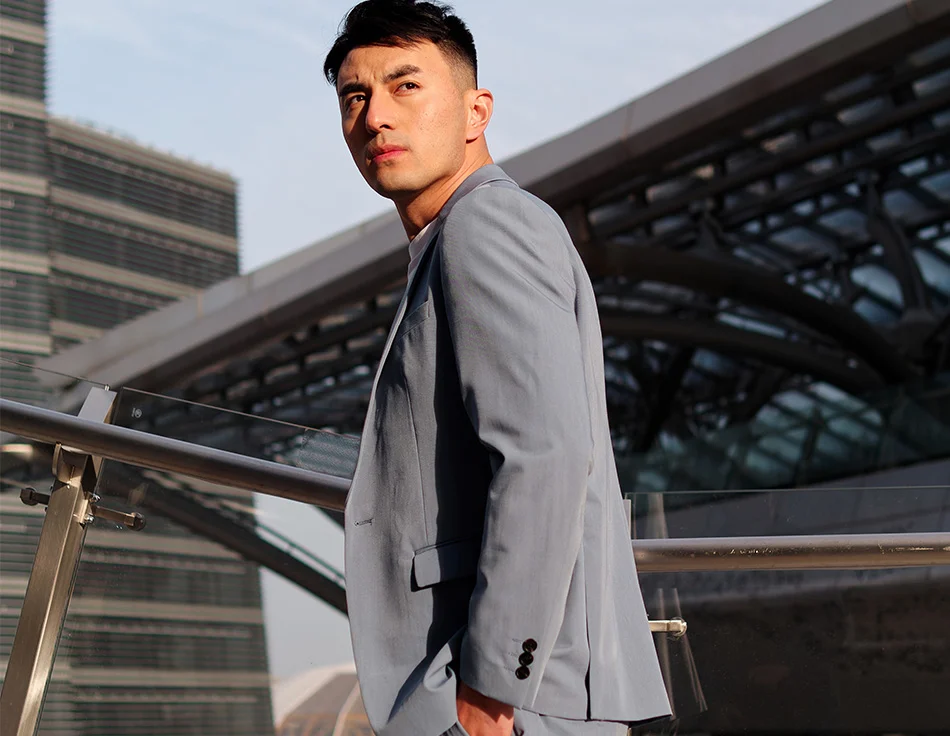 Man in a light blue suit standing by a railing in an urban setting, looking off into the distance - Botox to the Scrotum in Houston, TX